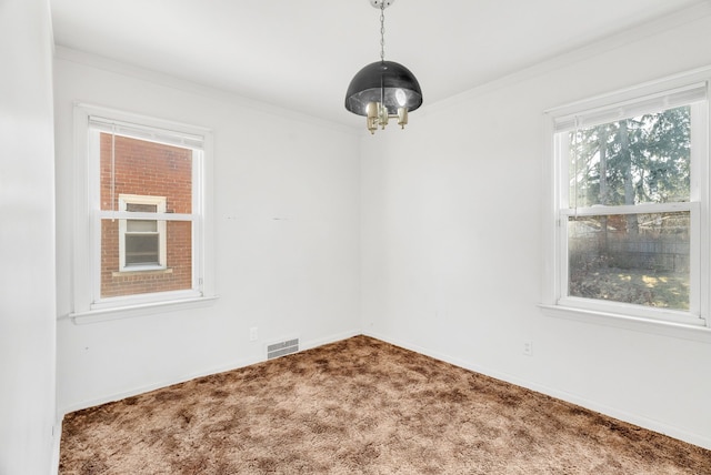 spare room with visible vents, carpet flooring, crown molding, baseboards, and a chandelier