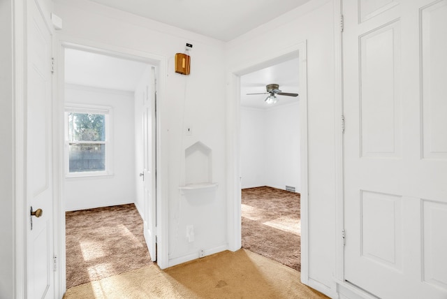 corridor featuring visible vents, baseboards, and light colored carpet