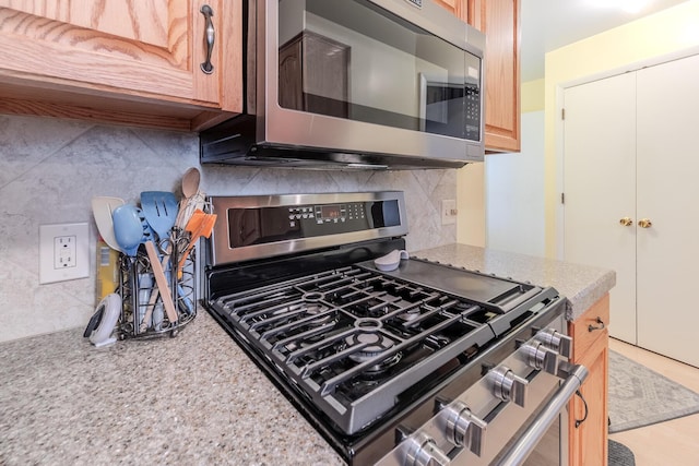 kitchen with decorative backsplash, light stone countertops, and stainless steel appliances