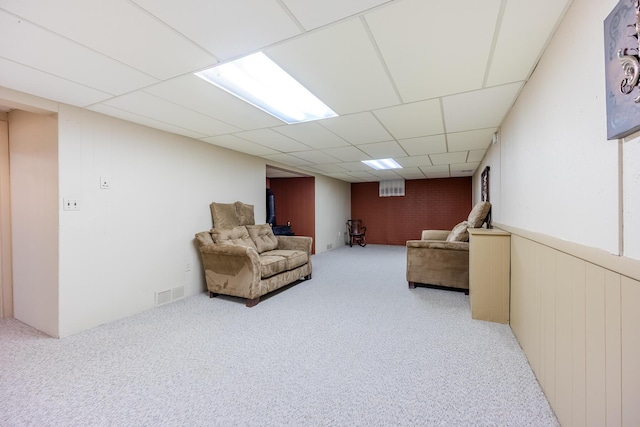 living area featuring light colored carpet, visible vents, and a drop ceiling