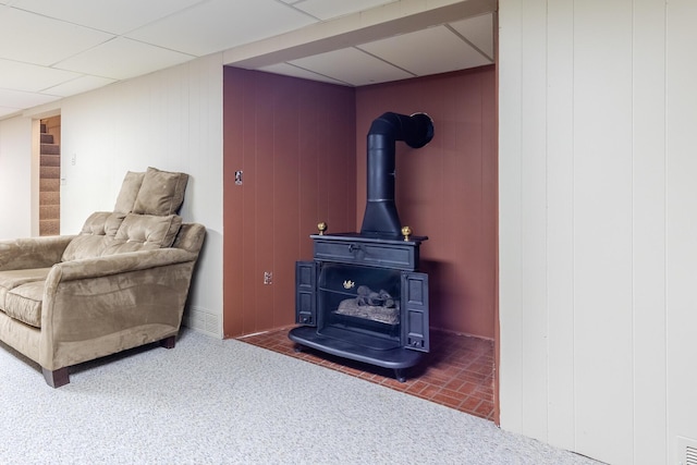 living room featuring stairway, a paneled ceiling, visible vents, and a wood stove