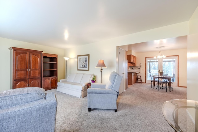 living area featuring baseboards, light carpet, and a notable chandelier