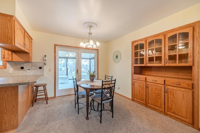 dining space with an inviting chandelier, light colored carpet, baseboards, and french doors