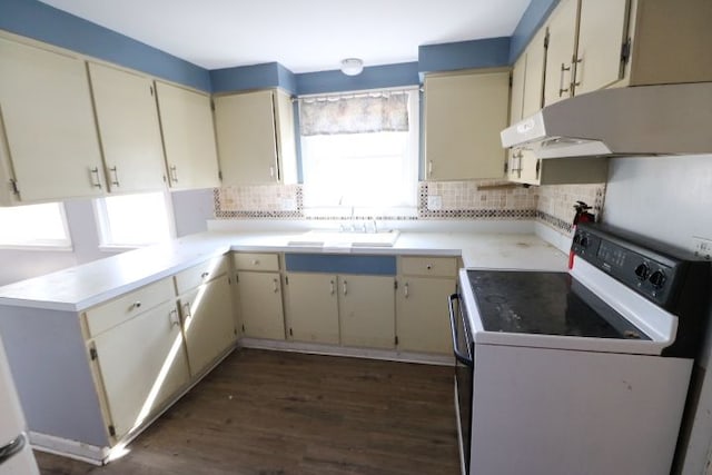 kitchen with under cabinet range hood, a sink, cream cabinets, white electric range oven, and decorative backsplash