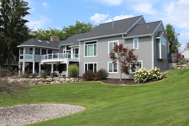 back of property with a lawn, a deck, a chimney, and a sunroom