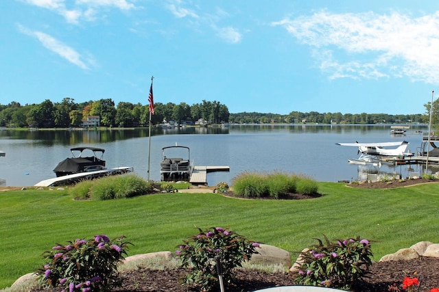 dock area featuring boat lift, a water view, and a lawn