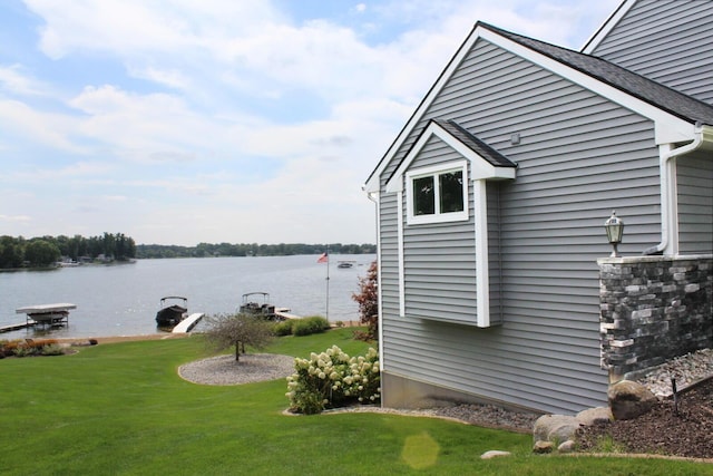 view of side of home featuring a lawn and a water view