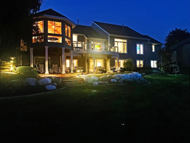 back of house at night with a balcony and a patio area