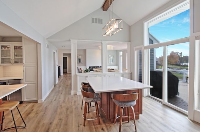 kitchen with decorative columns, visible vents, a breakfast bar area, and light wood-style flooring