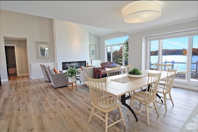 dining space featuring a fireplace, a water view, and light wood finished floors