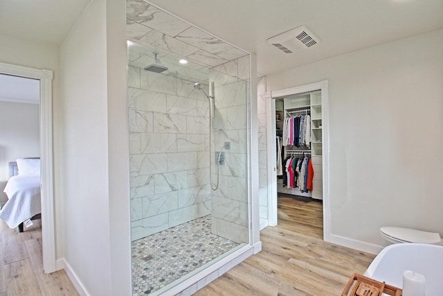 full bathroom with baseboards, wood finished floors, visible vents, and tiled shower