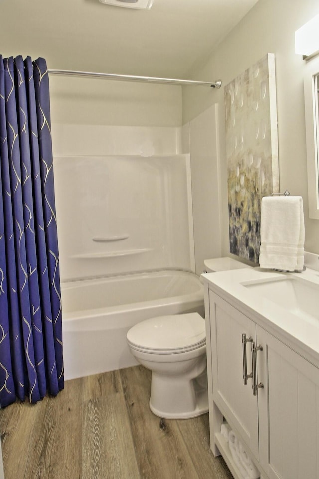 bathroom featuring toilet, shower / bath combo with shower curtain, vanity, and wood finished floors