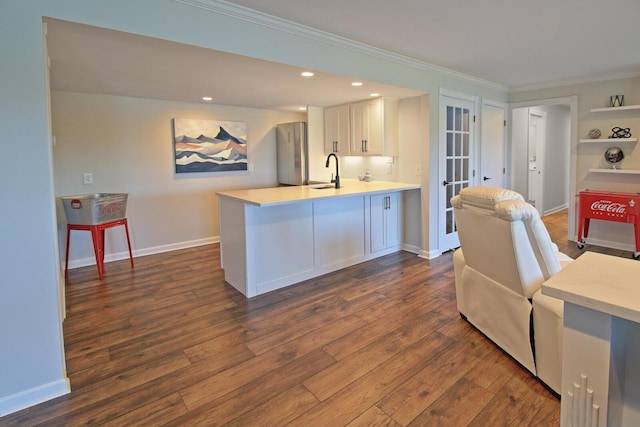 kitchen featuring dark wood-style floors, freestanding refrigerator, a sink, light countertops, and white cabinets