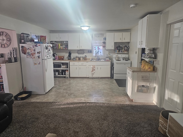 kitchen featuring a sink, range, white cabinetry, and freestanding refrigerator