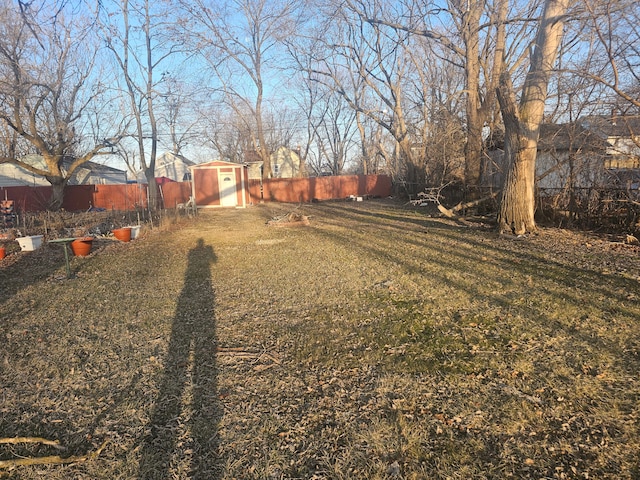 view of yard featuring an outdoor structure, a fenced backyard, and a shed