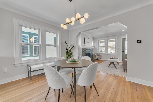 dining space featuring baseboards, light wood-style floors, and a fireplace