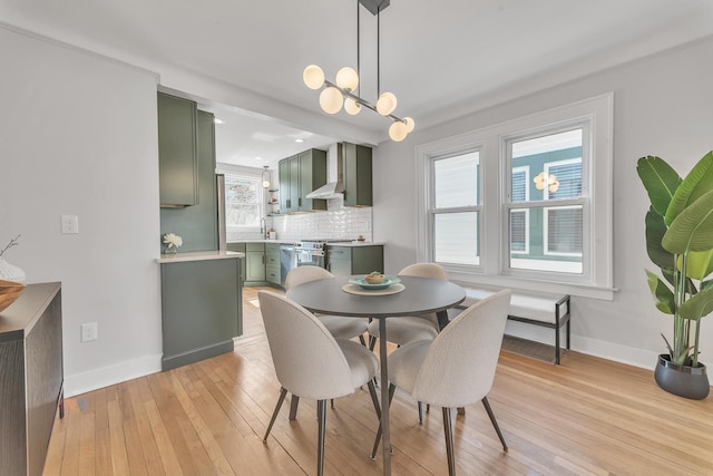 dining area with light wood finished floors, an inviting chandelier, and baseboards