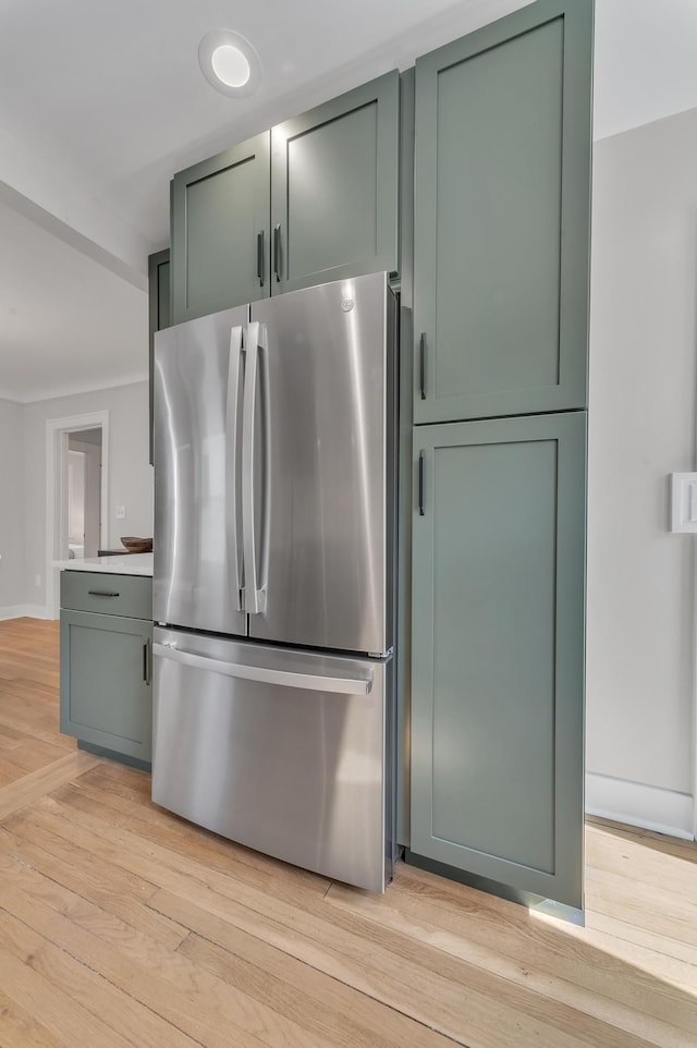 kitchen featuring light wood finished floors, light countertops, freestanding refrigerator, and green cabinetry