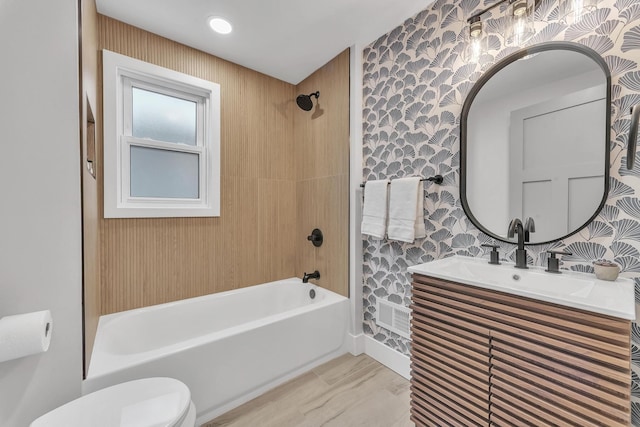 bathroom with shower / bathing tub combination, toilet, vanity, and wallpapered walls