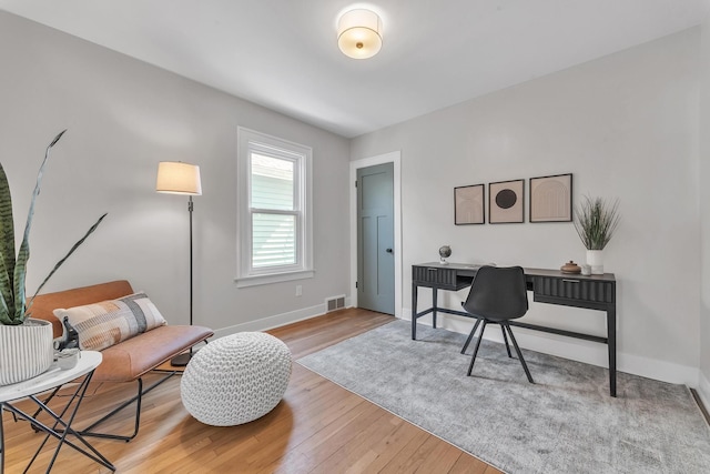 office space with baseboards, visible vents, and light wood finished floors