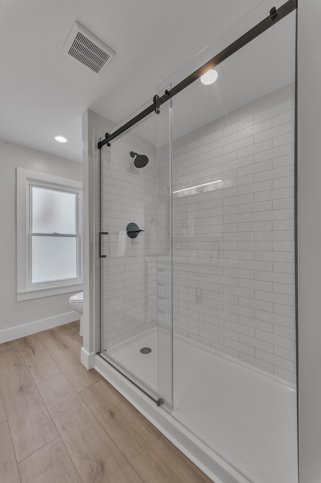 bathroom featuring visible vents, wood finished floors, toilet, and a stall shower