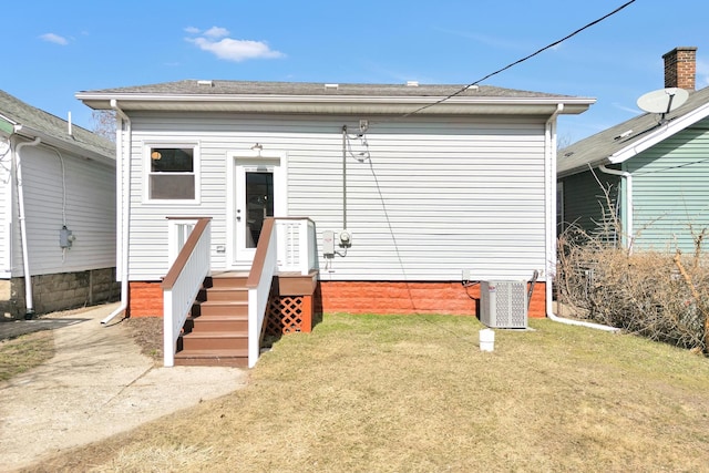 back of property with central air condition unit, a lawn, and a shingled roof