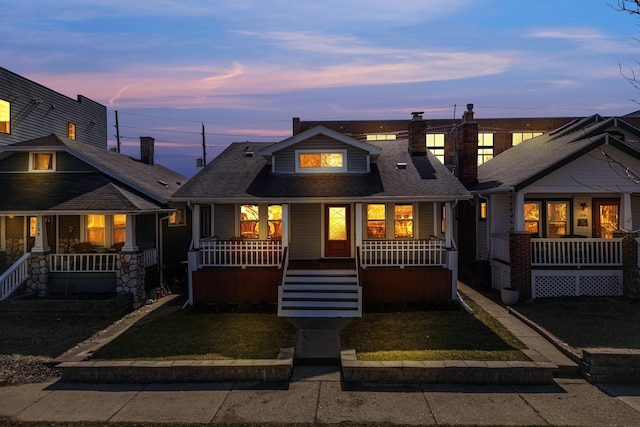 view of front of house featuring a porch, a front yard, and a shingled roof