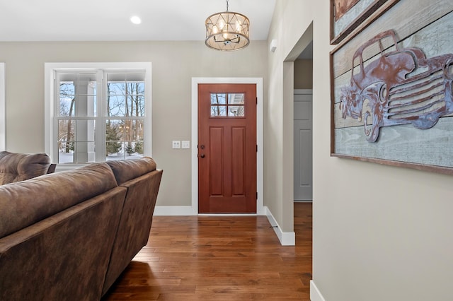 entrance foyer with baseboards, a notable chandelier, a healthy amount of sunlight, and wood finished floors