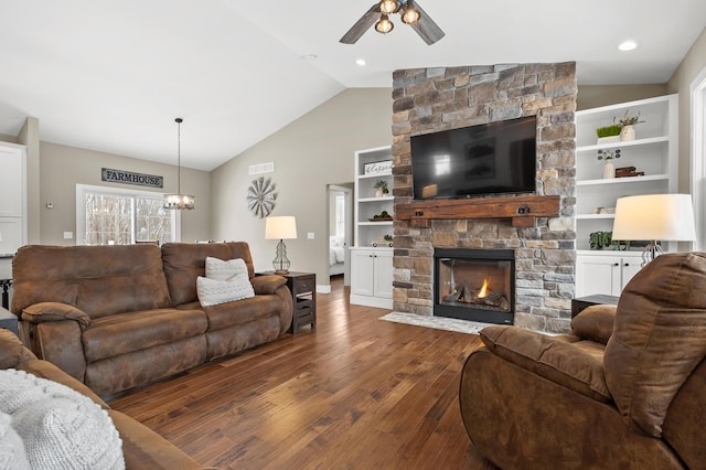 living area with visible vents, lofted ceiling, ceiling fan with notable chandelier, a fireplace, and wood finished floors