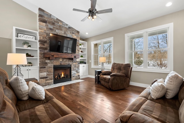 living area featuring a stone fireplace, lofted ceiling, baseboards, and hardwood / wood-style floors