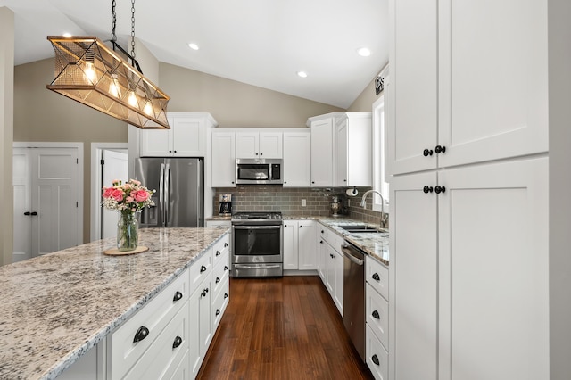 kitchen featuring a sink, backsplash, dark wood finished floors, appliances with stainless steel finishes, and lofted ceiling