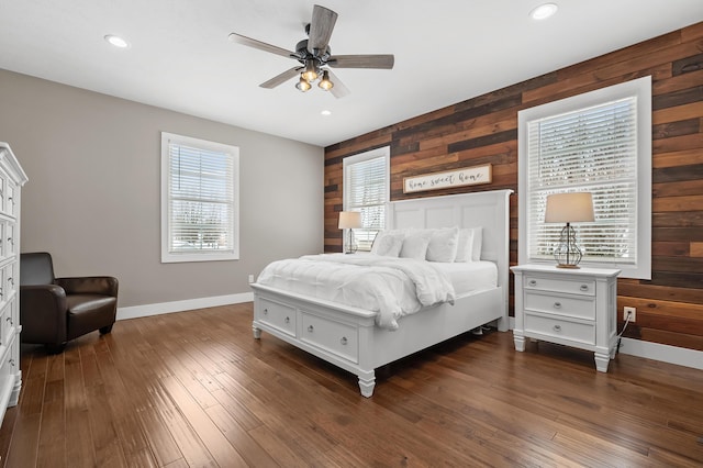 bedroom featuring dark wood finished floors, recessed lighting, baseboards, and wood walls