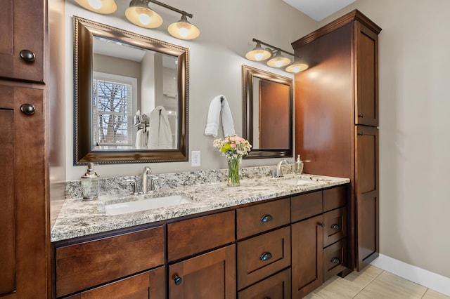 full bathroom with tile patterned flooring, double vanity, baseboards, and a sink