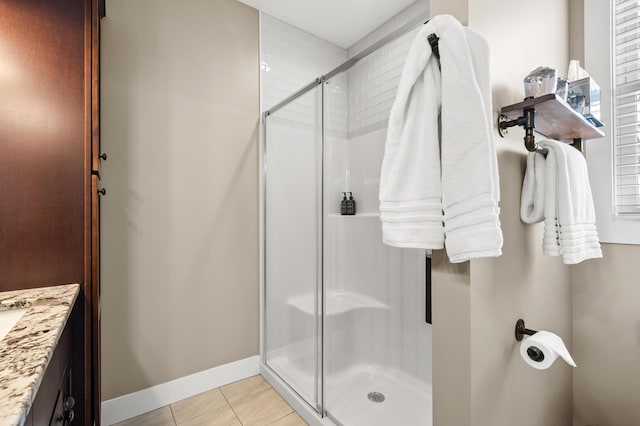 bathroom with tile patterned flooring, vanity, baseboards, and a stall shower