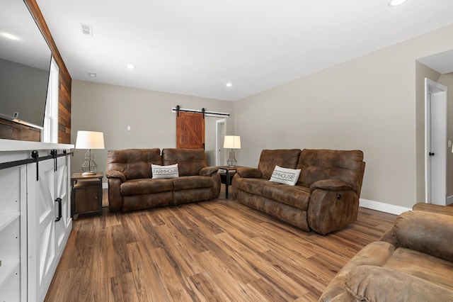 living area with visible vents, recessed lighting, a barn door, and wood finished floors