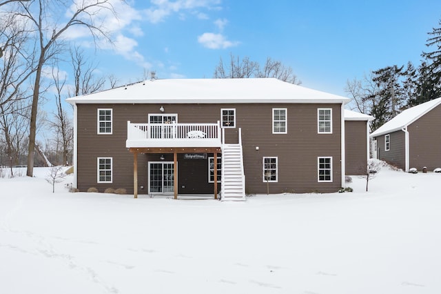 snow covered house with a deck and stairway