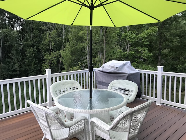 wooden deck featuring outdoor dining area and a wooded view