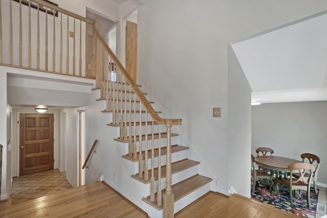 stairway with a towering ceiling and wood finished floors