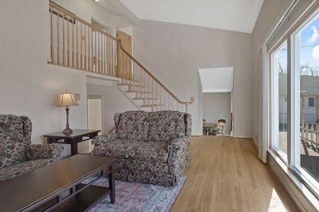 living area featuring stairway, wood finished floors, and a high ceiling