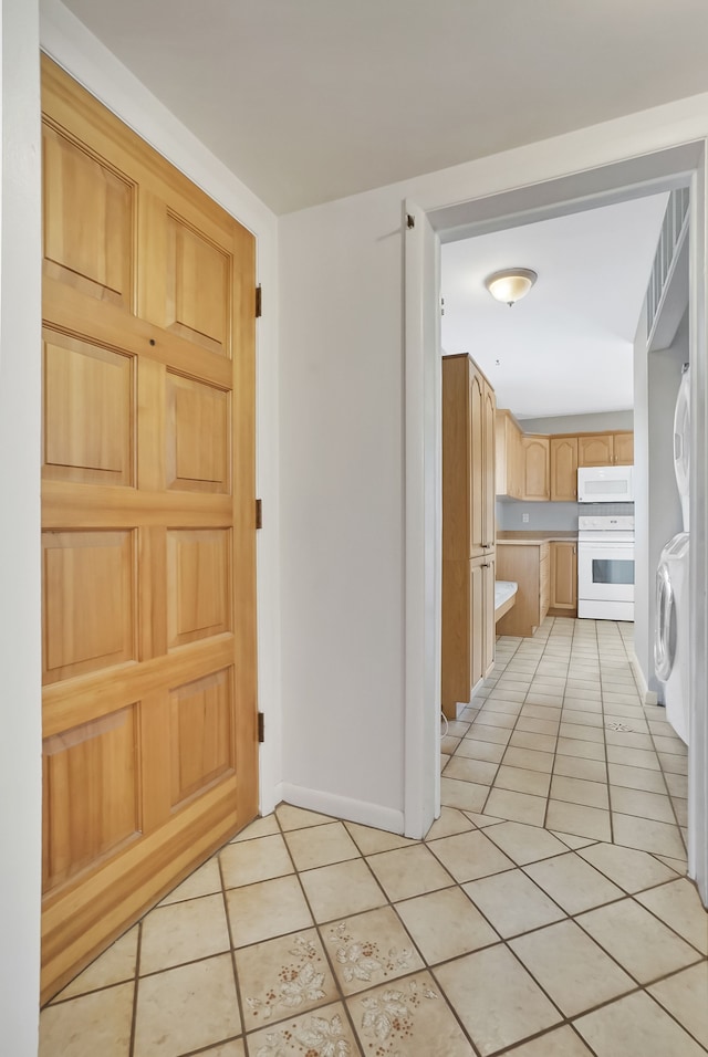 entryway featuring light tile patterned flooring, baseboards, and stacked washing maching and dryer