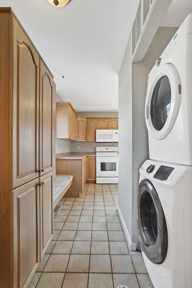 laundry room with laundry area, light tile patterned floors, baseboards, and stacked washing maching and dryer