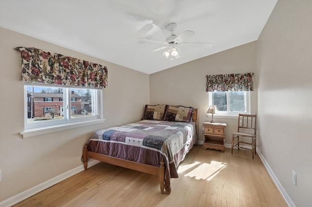 bedroom with a ceiling fan, vaulted ceiling, baseboards, and light wood-type flooring