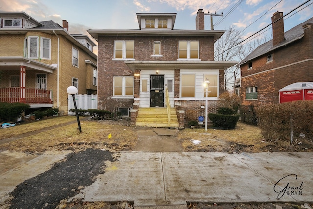 american foursquare style home featuring fence, brick siding, and a chimney