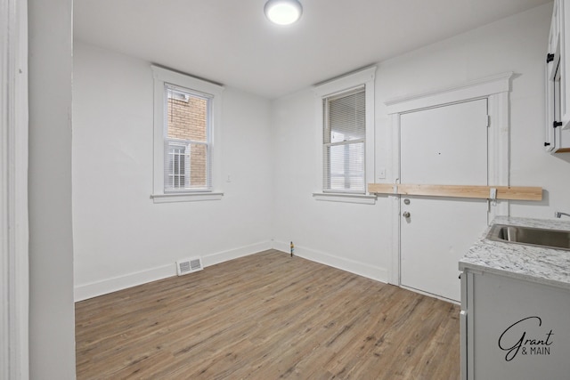 interior space featuring a sink, visible vents, baseboards, and light wood-style floors