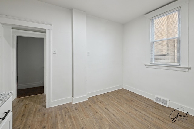 unfurnished room with baseboards, visible vents, and light wood-type flooring