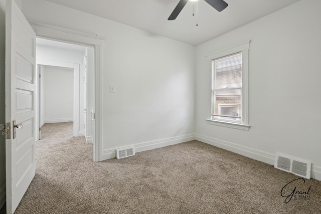 carpeted spare room with baseboards, visible vents, and ceiling fan