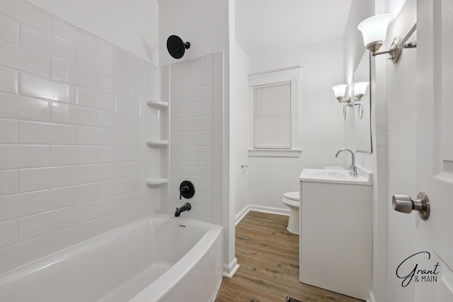 full bath featuring baseboards, toilet, vanity, wood finished floors, and washtub / shower combination