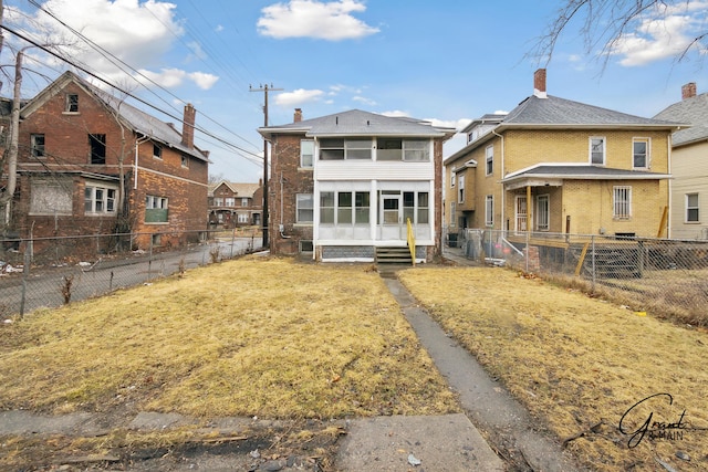 rear view of house with a fenced backyard, a sunroom, entry steps, a lawn, and brick siding