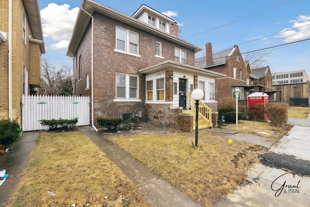 american foursquare style home featuring brick siding and fence