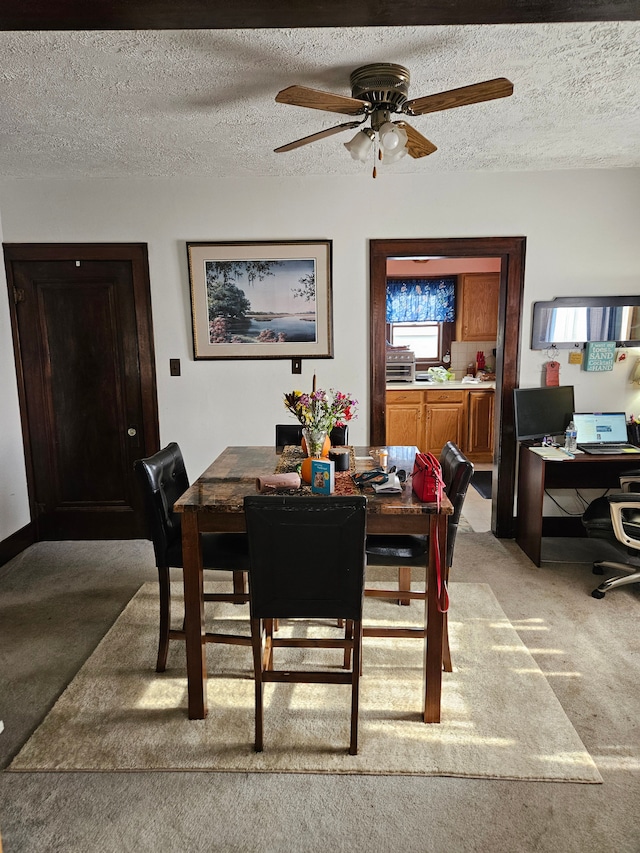 dining room with a textured ceiling, ceiling fan, and light carpet